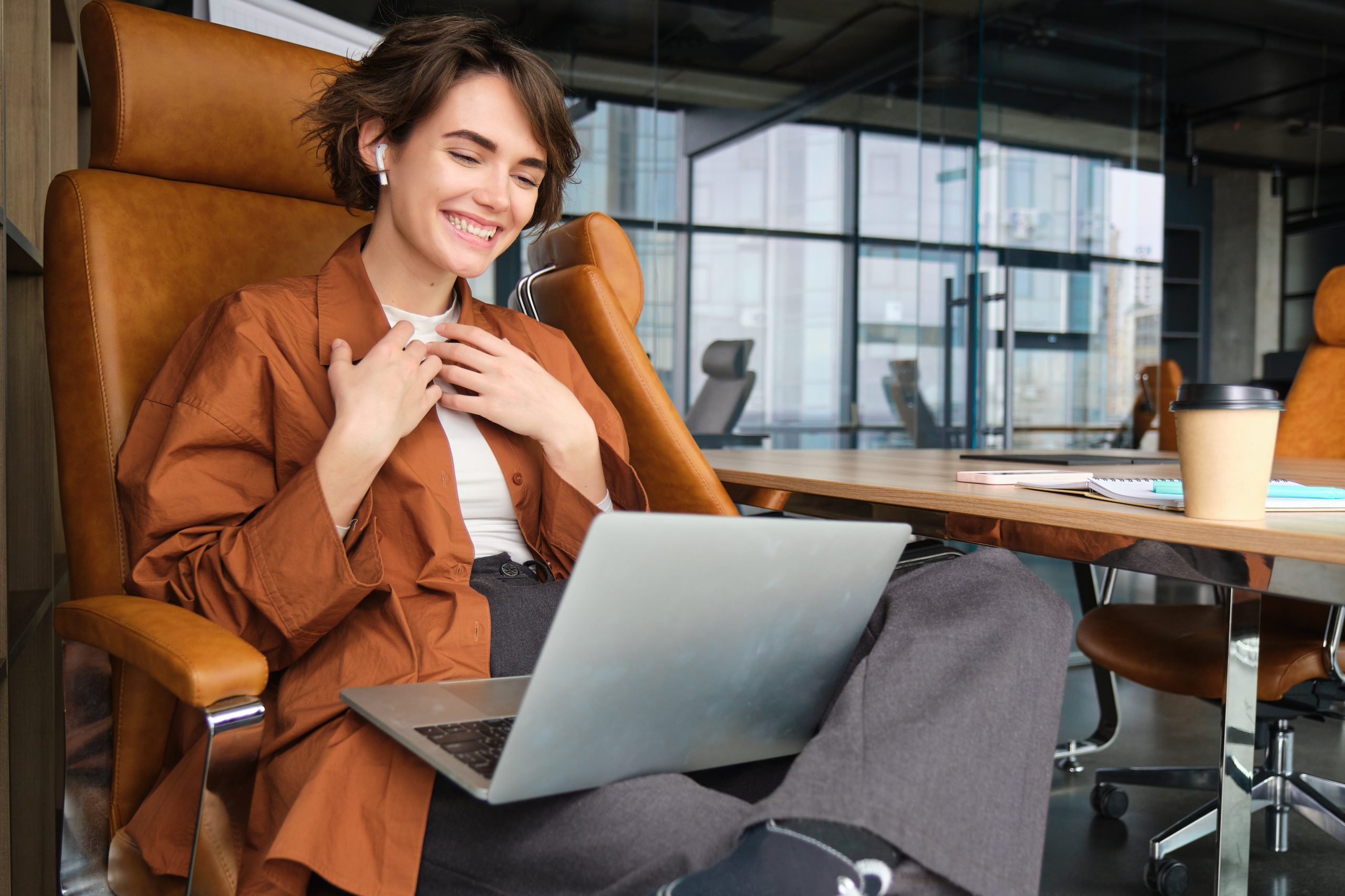 Portrait Of Woman In An Office, Manager Sits With Laptop, Looks Pleased And Amazed, Connects To Online Meeting On Computer, Feels Humbled